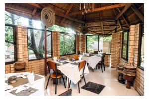 a dining room with tables and chairs and windows at Leon's Lodge in Choma