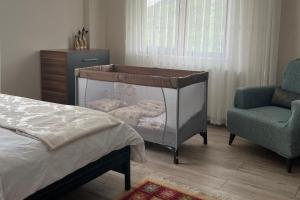 a baby crib in a bedroom with a chair at Hamsiköy Lifora House in Trabzon