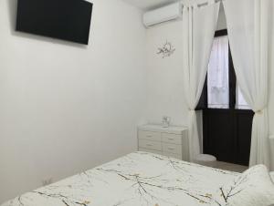 a white bedroom with a bed and a window at Oasi nel cuore di Noto in Noto