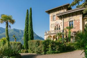 an old house with trees and mountains in the background at Villa Castiglioni Luxury Apartment in Laglio