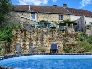 a house with a swimming pool in front of a stone wall at Chateau d'Impasse in Laferté-sur-Amance