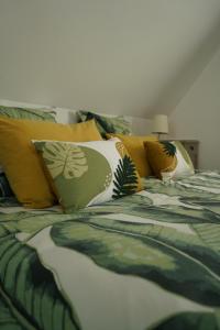 a bed with yellow and green pillows on it at L'Atelier des dépendances in Lipsheim