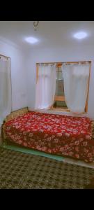 a bedroom with a bed with a red blanket and white curtains at Srinagar Stay House in Srinagar