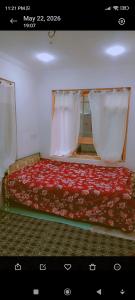 a bedroom with a bed with a red blanket and white curtains at Srinagar Stay House in Srinagar