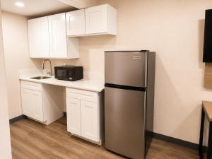 a kitchen with a stainless steel refrigerator and white cabinets at Travel Inn in Phoenix