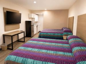 a hotel room with three beds and a flat screen tv at Travel Inn in Phoenix