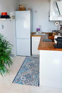 a kitchen with a refrigerator and a rug on the floor at Beachfront Apartment - 2 Terraces - Stunning Sunrises in Gibraltar +18 photos
