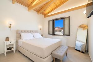 a white bedroom with a bed and a mirror at La Villa Du Soleil in Sami