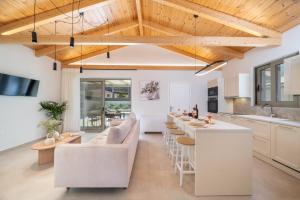 a kitchen and living room with white furniture and a bar at La Villa Du Soleil in Sami
