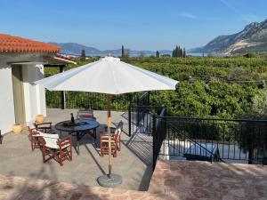 a patio with a table and a white umbrella at Olive Hill in Ancient Epidauros