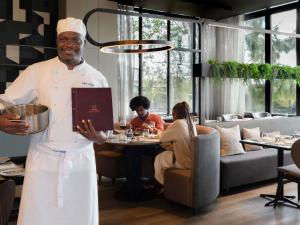 a chef standing in a restaurant holding a book at Novotel Lubumbashi in Lubumbashi +85 photos