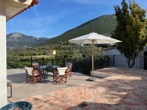 a patio with a table and chairs and an umbrella at Olive Hill in Ancient Epidauros