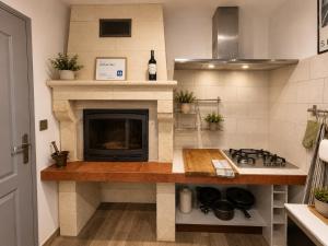 a kitchen with a counter with a stove and a fireplace at Au lit de Vin in Saint-Sulpice-de-Faleyrens
