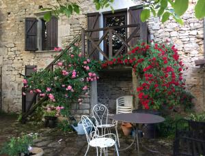 a table and chairs in front of a building with flowers at Ombre & Fraîcheur in Cazals