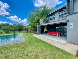 a backyard with a swimming pool and red chairs at Greens & Dreams in Parys