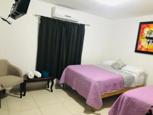 a bedroom with a purple bed and a chair and a window at Casa Bell in Ciudad Valles