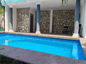 a swimming pool in front of a house with a stone wall at Casa Bell in Ciudad Valles