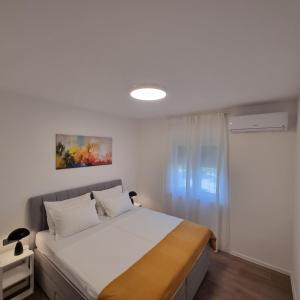 a bedroom with a bed with white sheets and a window at Apartman Zalar in Lopar