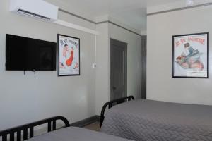 a bedroom with two beds and a flat screen tv at Gardner Hotel & Hostel in El Paso