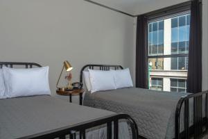 two beds in a room with a window at Gardner Hotel & Hostel in El Paso