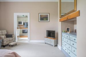 a bedroom with a dresser with a tv and a mirror at Bethby Beck Apartment Keswick at The Lairbeck in Keswick