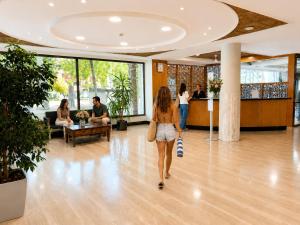 a woman walking through a lobby with people at Hotel Astoria Park in Lloret de Mar +74 photos