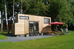 a tiny house with a picnic table and an umbrella at Tiny Gaumaise - Tiny house à Saint-leger in Saint-Léger