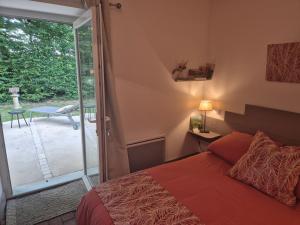 a bedroom with a bed and a sliding glass door at A La Maison in Les Repôts