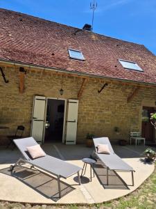 two lounge chairs and a table in front of a building at A La Maison in Les Repôts