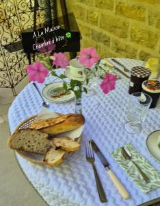a table with a plate of bread and flowers on it at A La Maison in Les Repôts