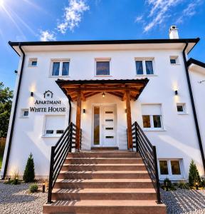a white house with stairs in front of it at Apartmani White House in Vrdnik