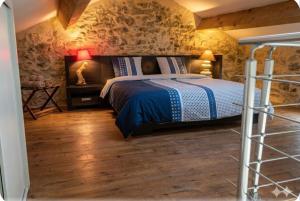 a bedroom with a bed and a stone wall at Maisonnette en pierre in Saint-Victor-de-Malcap