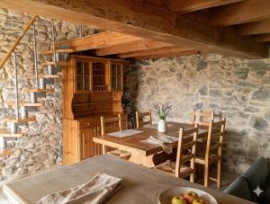 a dining room with a table and a stone wall at Maisonnette en pierre in Saint-Victor-de-Malcap
