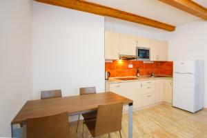 a kitchen with a wooden table and a white refrigerator at Apartmány Nad Rybníkem in Železná Ruda