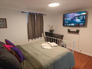 a bedroom with a bed and a flat screen tv at Spacious Basement Lower Suite 3BR Home Stay 1 King 2 Queen Beds 2 Car Parkings FIFA 2026 in Pickering