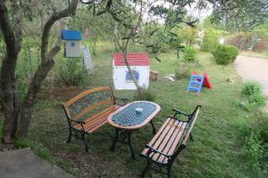 two benches and a table next to a tree at Efterpi seaside house in Chrysi Ammoudia