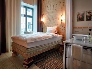 a bedroom with a bed and a window and a sink at 25hours Hotel The Royal Bavarian in Munich