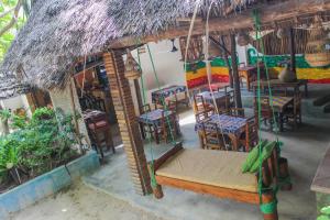 a room with a table and chairs and a room with a thatch roof at Sagando Bungalow in Michamvi +15 photos