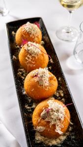 a black plate with four pastries on a table at Béni golf club Clervaux hôtel & Restaurant in Eselborn