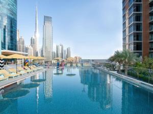 a swimming pool with chairs and a city skyline at Pullman Dubai Downtown in Dubai