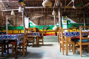 a restaurant with tables and chairs and a green wall at Sagando Bungalow in Michamvi