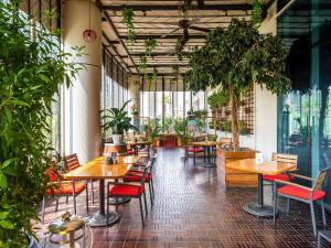 a restaurant with tables and chairs and potted plants at Pullman Dubai Downtown in Dubai