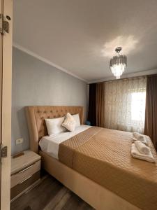 a bedroom with a large bed and a chandelier at Elite Apartaments in Curtea de Argeş