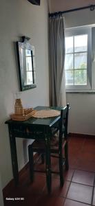 a table with a chair and a mirror and a window at Mar e Sol in Vila Nova de Milfontes