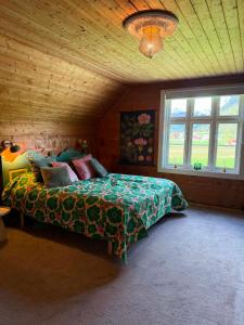 a bedroom with a bed with a green comforter and a window at Meiriet1936 in Fjarland
