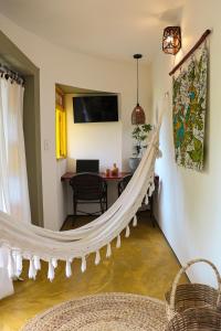 a hammock in a living room with a table at Pousada Barra Velha in Maragogi