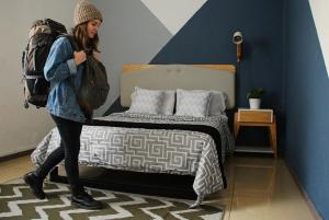a woman with a backpack standing next to a bed at Wanderlust District in Mexico City