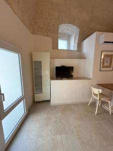 a living room with a tv and a table and a window at Neptune Stone House in Molfetta