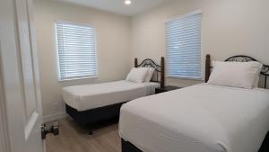 two beds in a room with white walls and windows at Rest Haven Motel in Los Angeles