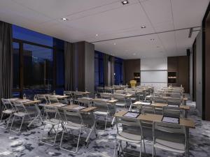 a classroom with tables and chairs in a room with windows at Novotel Tianjin Drum Tower in Tianjin
